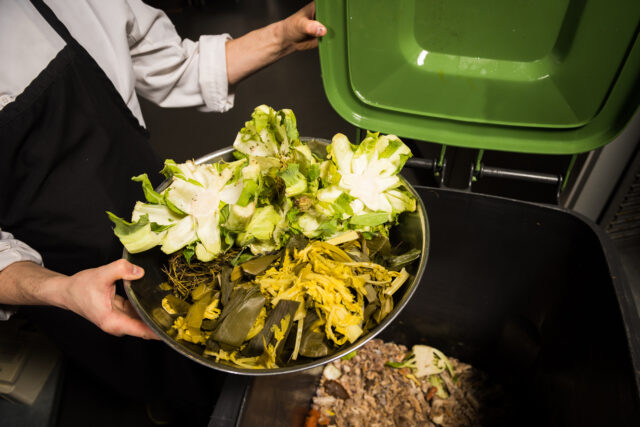 Chef emptying vegetable scraps into a composting bin - bio Collectors